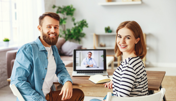 Веселый молодой человек и женщина улыбаются и смотрят в камеру, сидя за столом дома и делая видеозвонок психологу
 - Фото, изображение