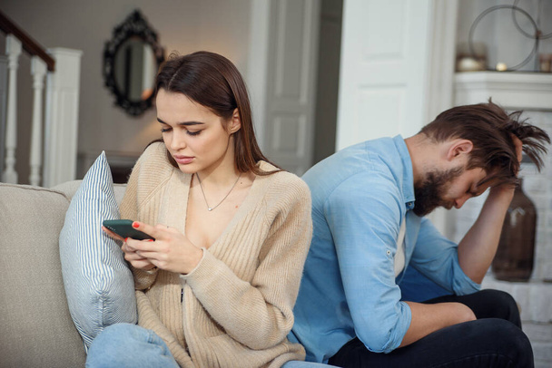 Modern couple at home. Man and woman concentrated on messaging with smartphones, ignoring each other and spending time on social media. - Fotó, kép