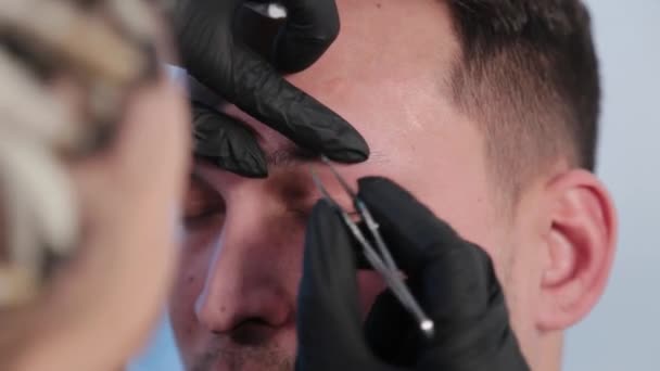 Eyebrow plucks eyebrows to a man in a beauty salon. - Footage, Video