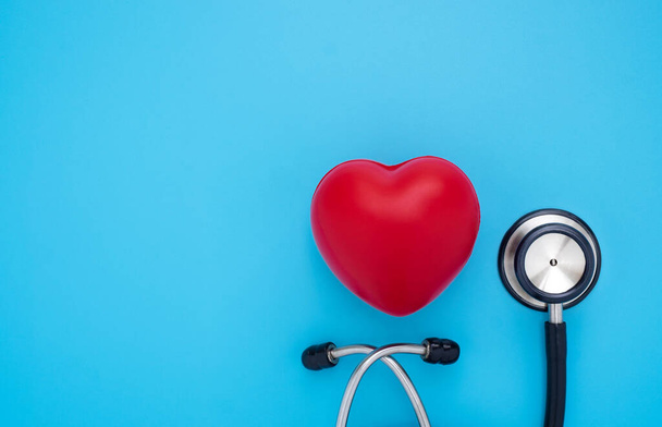 Close-up of Black stethoscope with red heart of doctor for checkup on blue background. Stethoscope equipment of medical use to diagnose hear sound. Health care and cardiology concept with copy  - 写真・画像