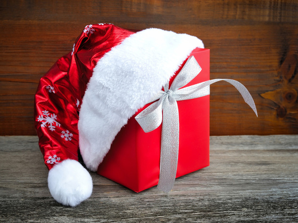 Sombrero de Papá Noel con regalo de Navidad rojo sobre fondo de madera
 - Foto, imagen