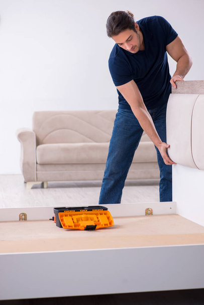 Jovem empreiteiro masculino instalando móveis em casa - Foto, Imagem
