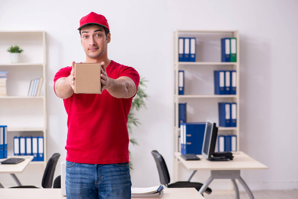 Junger männlicher Kurier bringt Briefkasten ins Büro - Foto, Bild