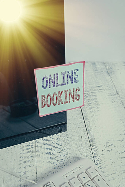 Text sign showing Online Booking. Conceptual photo Reservation through internet Hotel accommodation Plane ticket Notation paper taped to black computer monitor screen near white keyboard. - Photo, Image