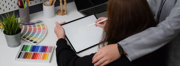 Oříznutý záběr návrhářky pracující na maketové tabletě s perem stylus při konzultacích s kolegyní na módním pracovišti - Fotografie, Obrázek