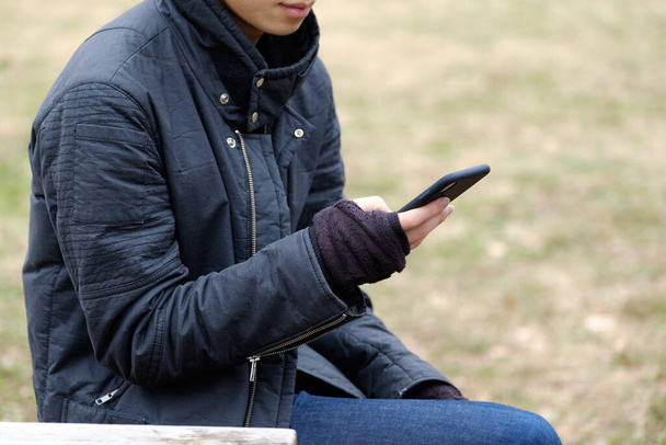 Hombre japonés utiliza guantes sin dedos para operar su teléfono inteligente al aire libre en invierno
 - Foto, Imagen