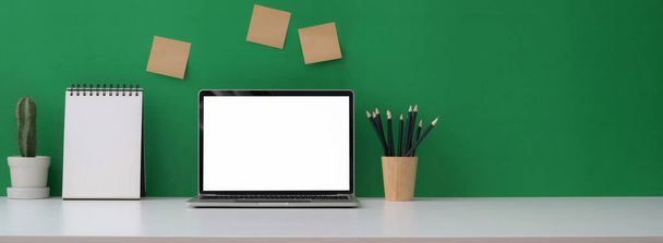 Vista de perto do espaço de trabalho criativo com laptop mock-up, calendário, decoração de papelaria e espaço de cópia na mesa branca
  - Foto, Imagem