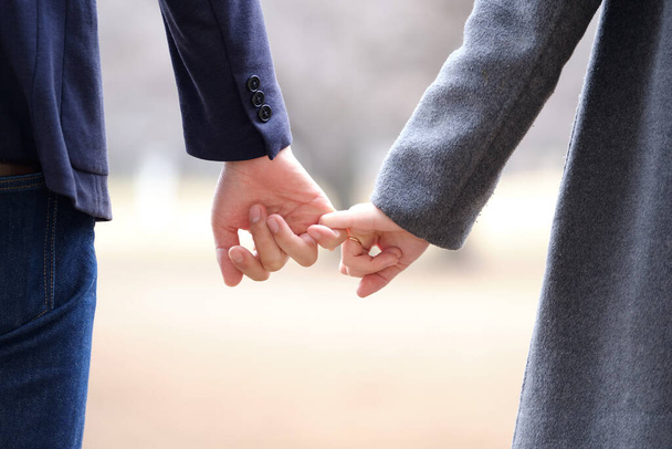 A couple of Japanese men and women hold their pinkies together in a park in winter - Foto, imagen