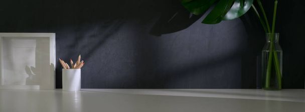 Vue rapprochée de l'espace de travail branché avec cadre maquette, papeterie, décorations et espace de copie sur table blanche avec mur gris
  - Photo, image