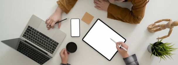 Overhead-Aufnahme von Geschäftsleuten, die ihre Geschäftsstrategie mit digitalen Mock-up-Geräten auf weißem Tisch beraten - Foto, Bild