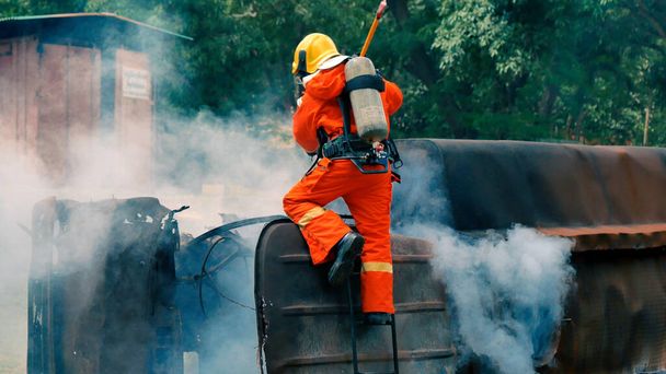 消火ホース化学水フォームスプレーエンジンを使用して炎と戦う消防士。消防士は、保護のためのハード帽子、ボディセーフスーツの制服を着用してください。消火器の救助訓練 - 写真・画像