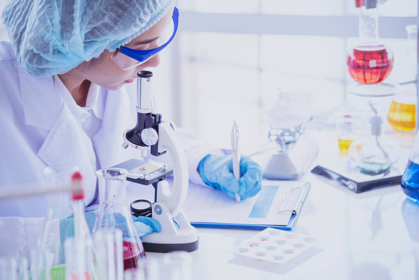 女性科学者は顕微鏡を見て、科学試験管は、実験室の研究実験生物学における科学サンプルを分析し、ウイルスに対するワクチンを栽培する。化学科学研究室のコンセプト - 写真・画像