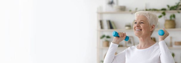 Jubilación activa. Deportiva mujer mayor haciendo ejercicio con mancuernas en casa
 - Foto, Imagen
