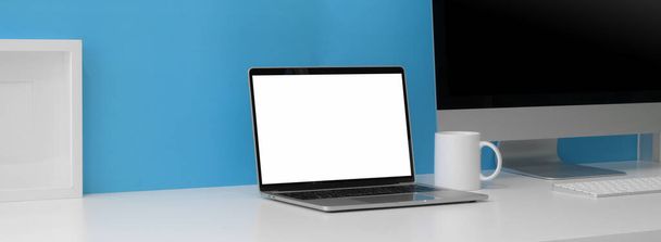 Captura recortada de espacio de trabajo creativo con computadora portátil de pantalla en blanco, computadora y espacio de copia en la mesa blanca con estante en la pared azul claro
 - Foto, imagen