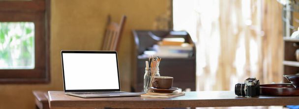 Vue rapprochée du lieu de travail vintage avec ordinateur portable maquillé, tasse à café, fournitures sur bureau en bois
    - Photo, image
