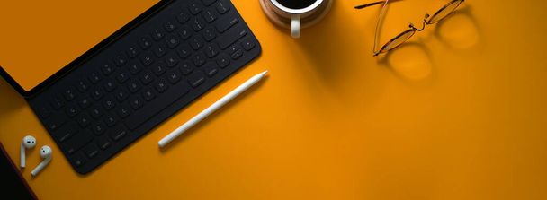 Vista superior da mesa de trabalho criativa com dispositivo digital, suprimentos e espaço de cópia na mesa amarela
  - Foto, Imagem