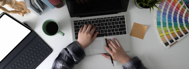 Εναέρια λήψη γυναικών ελεύθερων επαγγελματιών που εργάζονται στο έργο της με laptop, mock-up tablet και προμήθειες σχεδιαστών σε λευκό τραπέζι - Φωτογραφία, εικόνα