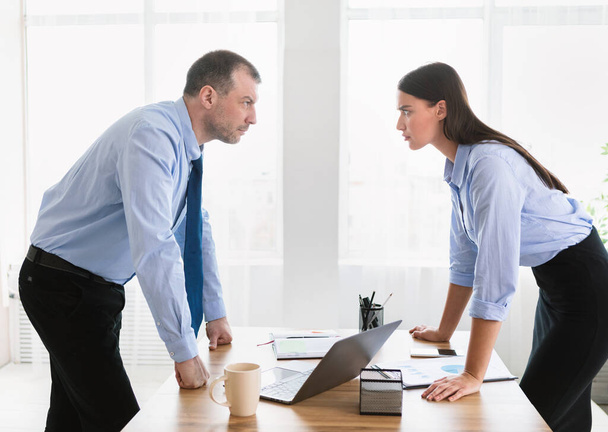 Uomo d'affari e donna d'affari che hanno conflitti sul lavoro in piedi in ufficio
 - Foto, immagini