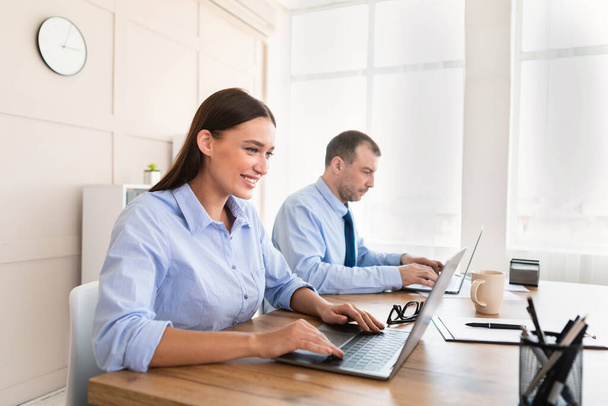 Bizneswoman i biznesmen pracujący na laptopie siedzi w nowoczesnym biurze - Zdjęcie, obraz