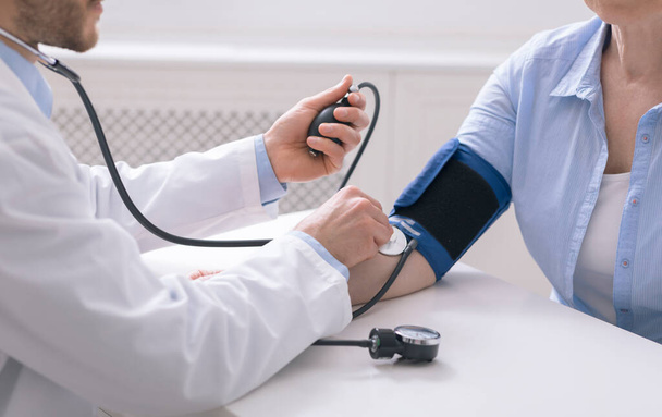 Médico que mede a pressão arterial para paciente idoso
 - Foto, Imagem