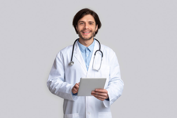 Alegre médico usando tableta digital en las manos
 - Foto, Imagen