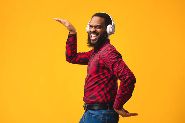 Lachende afro man geniet van muziek met koptelefoon - Foto, afbeelding
