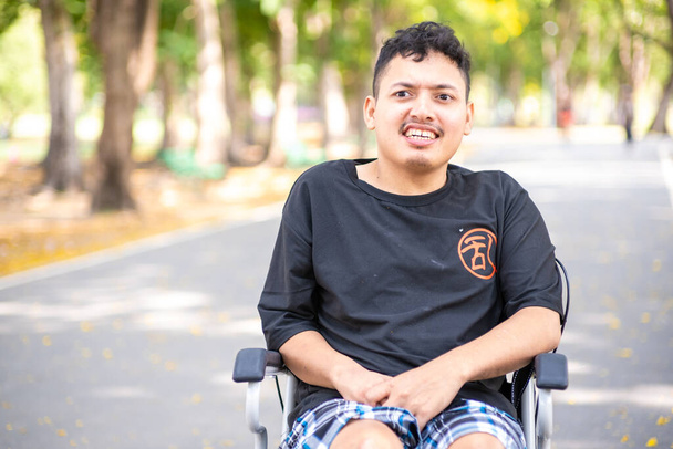 Desactivar asiático hombre sentado en silla de ruedas en ciudad parque esperanza concepto - Foto, imagen