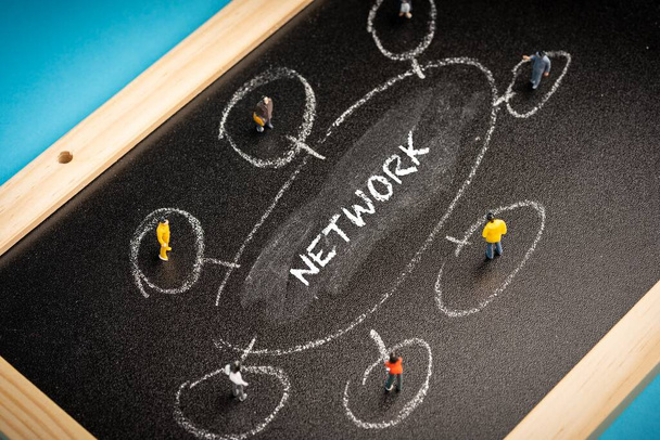 Business concept: Networking. A group of miniatures people on a chalkboard with "NETWORK" wordings - Photo, Image