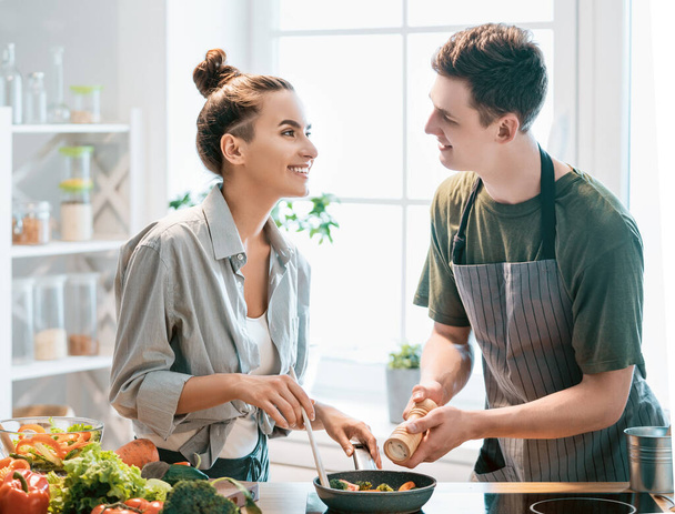 Healthy food at home. Happy loving couple is preparing the proper meal in the kitchen.   - Foto, Bild