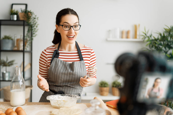 Young confident woman is talking on digital camera recording vlog about cooking. - Foto, Imagem