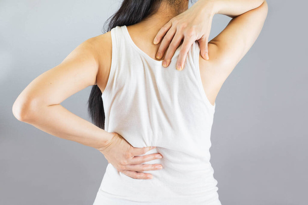 Woman wore white undershirt,hands holding her back in pain and waist .Health-care Concept.Selective focus - Foto, imagen