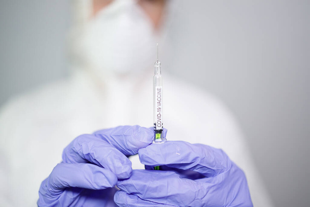 Mikrobiológus vagy orvos kék sebészeti kesztyűvel, fecskendőt tartva a vakcinával a gyorsan terjedő Coronavirus ellen. COVID-19 vakcina koncepciója - Fotó, kép