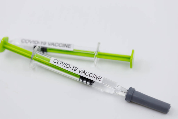 Dos inyecciones de jeringa con la vacuna para el coronavirus sobre fondo blanco con espacio para copias. Concepto de vacuna COVID-19
 - Foto, imagen