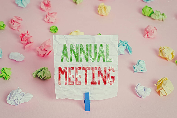 Text sign showing Annual Meeting. Conceptual photo Yearly gathering of an organization interested shareholders Colored crumpled papers empty reminder pink floor background clothespin. - Photo, Image