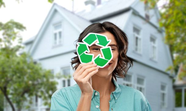 улыбающаяся женщина смотрит через зеленый знак переработки
 - Фото, изображение