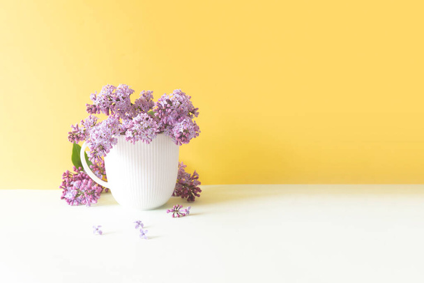 white cup with syringa flowers on yellow background - Fotografie, Obrázek