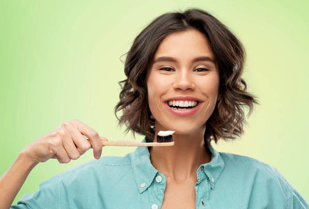 femme souriante avec dentifrice sur brosse à dents en bois - Photo, image
