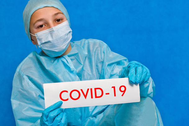 Jonge dokter toont een bord met covid-19.. - Foto, afbeelding