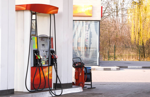 Handle fuel nozzle to refuel, fuel oil gasoline dispenser at petrol filling station,Fire extinguisher is installed for safety, Gas station in a service in warm sunset.Head fuel vehicle refueling facility - Photo, Image