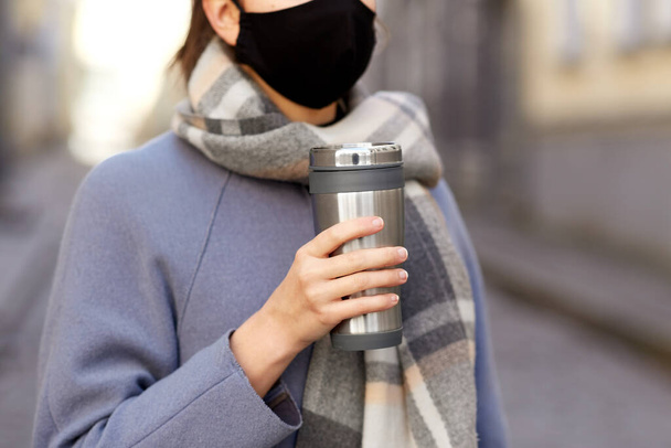 woman in reusable mask with tumbler in city - Foto, Bild