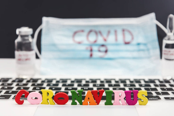 2019 Coronavirus, aşıyı ampul ve dizüstü bilgisayarla aşılayarak aşı maskesine yazıyor. Dünya çapında bir salgın. Virüs aşısı arama konsepti - Fotoğraf, Görsel