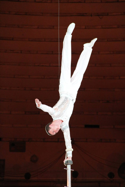 Gomel / Belarus - May 20, 2018 : Circus number. Man equilibrist showing tricks during performance of gymnasts in circus. Gymnast equilibriss under circus dome. Gymnast performing unimaginable tricks under dome of circus - Foto, Imagem
