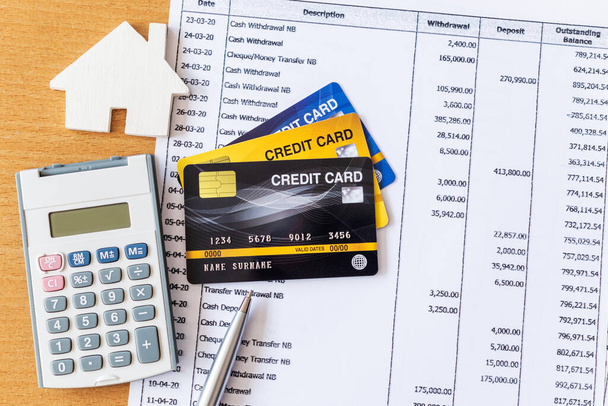 Modelo de casa y calculadora en estado de cuenta del banco y tarjeta de crédito en una mesa de madera. concepto de hipoteca de compra de vivienda
 - Foto, Imagen
