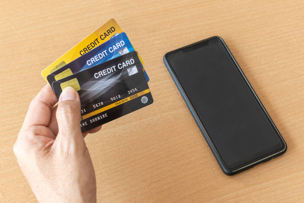 Facet z kartami kredytowymi i smartfonem. Zakupy on-line w Internecie za pomocą smartfona - Zdjęcie, obraz