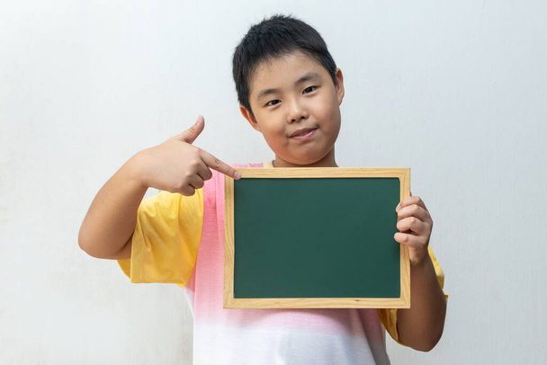 Niño asiático sosteniendo tablero vacío. Concepto de educación
 - Foto, Imagen