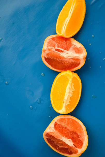 Draufsicht auf geschnittene Grapefruits und Orangen auf blauem Hintergrund mit Kopierraum, geschnittene Stücke von verschiedenen Zitrusfrüchten, geschnittene Zitrusfrüchte saftig - Foto, Bild