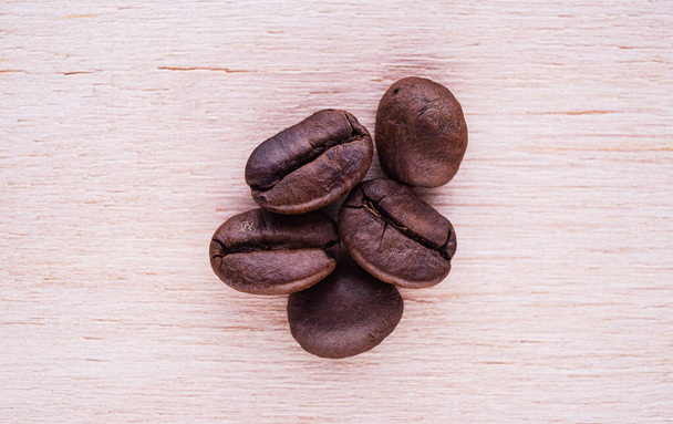 Öt pörkölt kávébab egy lapos fa felületen felülről lefelé kompozíció - Fotó, kép