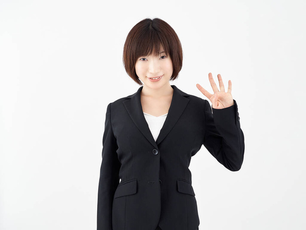 Une employée de bureau japonaise pose avec une pose à quatre pointes sur un fond blanc
 - Photo, image