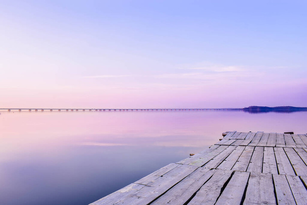 Muelle en el fondo del mar con una superficie brillante, que refleja el cielo rosa-azul
 - Foto, Imagen