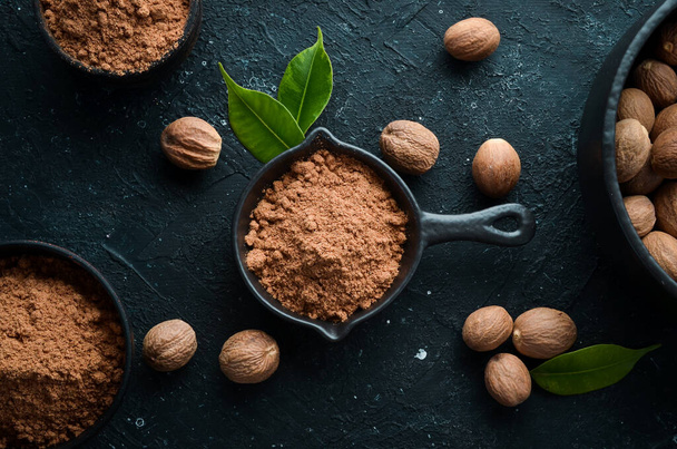 Ground nutmeg in bowl on black stone background. Fragrant Indian spices. Free space for your text. Top view. - Φωτογραφία, εικόνα
